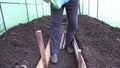 Man hammer wood stake to enclose greenhouse path with planks. 4K