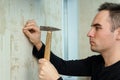 A man hammers a nail into plaster wall under the Wallpaper Royalty Free Stock Photo