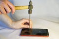 A man hammers a nail into the screen of a smartphone. Royalty Free Stock Photo