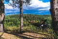 Man in a hammock on pine forest mountain, outdoor traveler relax, enduro off road motorcycle