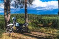 Man in a hammock on pine forest mountain, outdoor traveler relax, enduro off road motorcycle