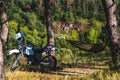 Man in a hammock on pine forest mountain, outdoor traveler relax, enduro off road motorcycle