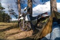 Man in a hammock on pine forest mountain, outdoor traveler relax, enduro off road motorcycle