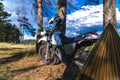 Man in a hammock on pine forest mountain, outdoor traveler relax, enduro off road motorcycle