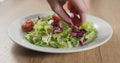 Man hand adding cherry tomatoes to salad leaves Royalty Free Stock Photo