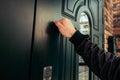 man hand in a black jacket knocks on a dark green wooden door. Anybody home. Royalty Free Stock Photo