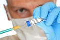Man hand in blue glove hold small vial with coronavirus vaccine label own design dummy barcode, to inject it with green orange Royalty Free Stock Photo