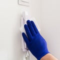 Man hand in blue glove washing door phone with moist napkin
