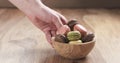 Man hand bring bowl with mixed colors macarons on table