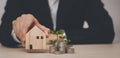 Man hand choosing mini wood house model and Coins stack and leaf with line graph on wood table, Planning buy Real Estate, Planning Royalty Free Stock Photo