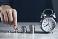 Man hand coins with clock on desk