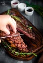 Man hand cutting grilled t bone steak on wooden Royalty Free Stock Photo