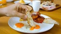 Man hand dip toasted bread in fried egg yolk in restaurant on breakfast or lunch