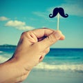 man hand with a fake moustache on the beach, with a filter effect