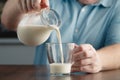 Man hand flowing milk from jar into glass