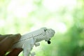 Man hand flying toy plane against blur green background