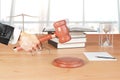 Man hand with gavel, books and hourglass on wooden table