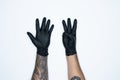 A man hand and gestures in Black rubber glove shows eight sign isolated on white background