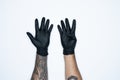 A man hand and gestures in Black rubber glove shows nine sign isolated on white background