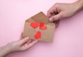 Man hand gives an envelope with a heart to a woman in hand on a pink background Royalty Free Stock Photo