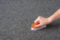 Man hand without gloves cleaning gray carpet with brush. dry cleaning technique