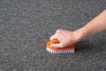 Man hand without gloves cleaning gray carpet with brush. dry cleaning technique