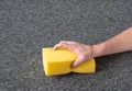 Man hand without gloves cleaning gray carpet with yellow sponge. dry cleaning technique