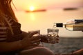 Man hand gracefully pouring white wine while girlfriend holding glasses. Couple enjoy beverage on sunset near sea Royalty Free Stock Photo