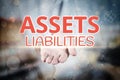 Man hand holding Assets Liabilities text on blurry home icon pro