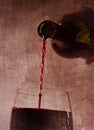 Man hand holding Bottle pouring red wine filling Glass on arty background
