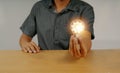 Man hand holding a bright light bulb cog icon sitting on desk business enterprise innovation ideas to inspire development using Royalty Free Stock Photo