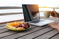 Man hand holding coffee and fresh fruit working on laptop Royalty Free Stock Photo