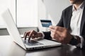 Man hand holding credit card and using laptop computer. Businessman or entrepreneur working at office. Royalty Free Stock Photo