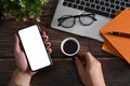 Man holding cup of coffee and using smart phone on wooden desk. Royalty Free Stock Photo