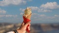 Man hand holding delicious ice cream with macadamia nuts and vanilla waffle cone with blue sky background Royalty Free Stock Photo