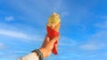 Man hand holding delicious ice cream with macadamia nuts and vanilla waffle cone with blue sky Royalty Free Stock Photo