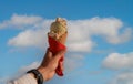 Man hand holding delicious ice cream with macadamia nuts and vanilla waffle cone with blue sky Royalty Free Stock Photo