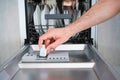 Putting tab into dishwasher, close up. A man hand holding dishwasher detergent tablet. Dishwasher machine full loaded Royalty Free Stock Photo