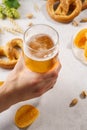 Man hand holding a glass of light beer. Various snacks around Royalty Free Stock Photo