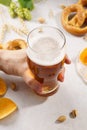 Man hand holding a glass of light beer. Various snacks around Royalty Free Stock Photo