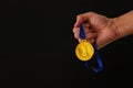 Man hand holding gold medal against black background. Award and victory concept. Royalty Free Stock Photo