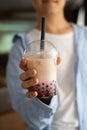 Man hand holding iced milk bubble tea with tapioca pearls and shows it to camera, traditional drink of Taiwan Royalty Free Stock Photo