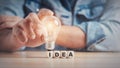 Man hand holding a light bulb on a wooden block with Word Ideas. innovation concept Royalty Free Stock Photo