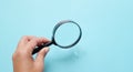 Man Hand holding Magnifying glass  on a blue backgrou Royalty Free Stock Photo