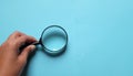 Man Hand holding Magnifying glass  on a blue backgrou Royalty Free Stock Photo