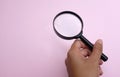 Man hand holding  Magnifying glass  on a  pink pastel backgroun Royalty Free Stock Photo