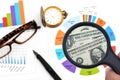 Man hand holding magnifying glass to see US dollar banknotes on spreadsheet and charts graphs paper. Royalty Free Stock Photo