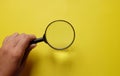 Man Hand holding Magnifying glass  on a yellow backgrou Royalty Free Stock Photo