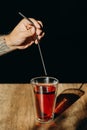A man hand holding metal straw or stainless straw above a glass of red sweet drink on wooden table Royalty Free Stock Photo