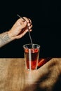 A man hand holding metal straw or stainless straw above a glass of red sweet drink on wooden table Royalty Free Stock Photo